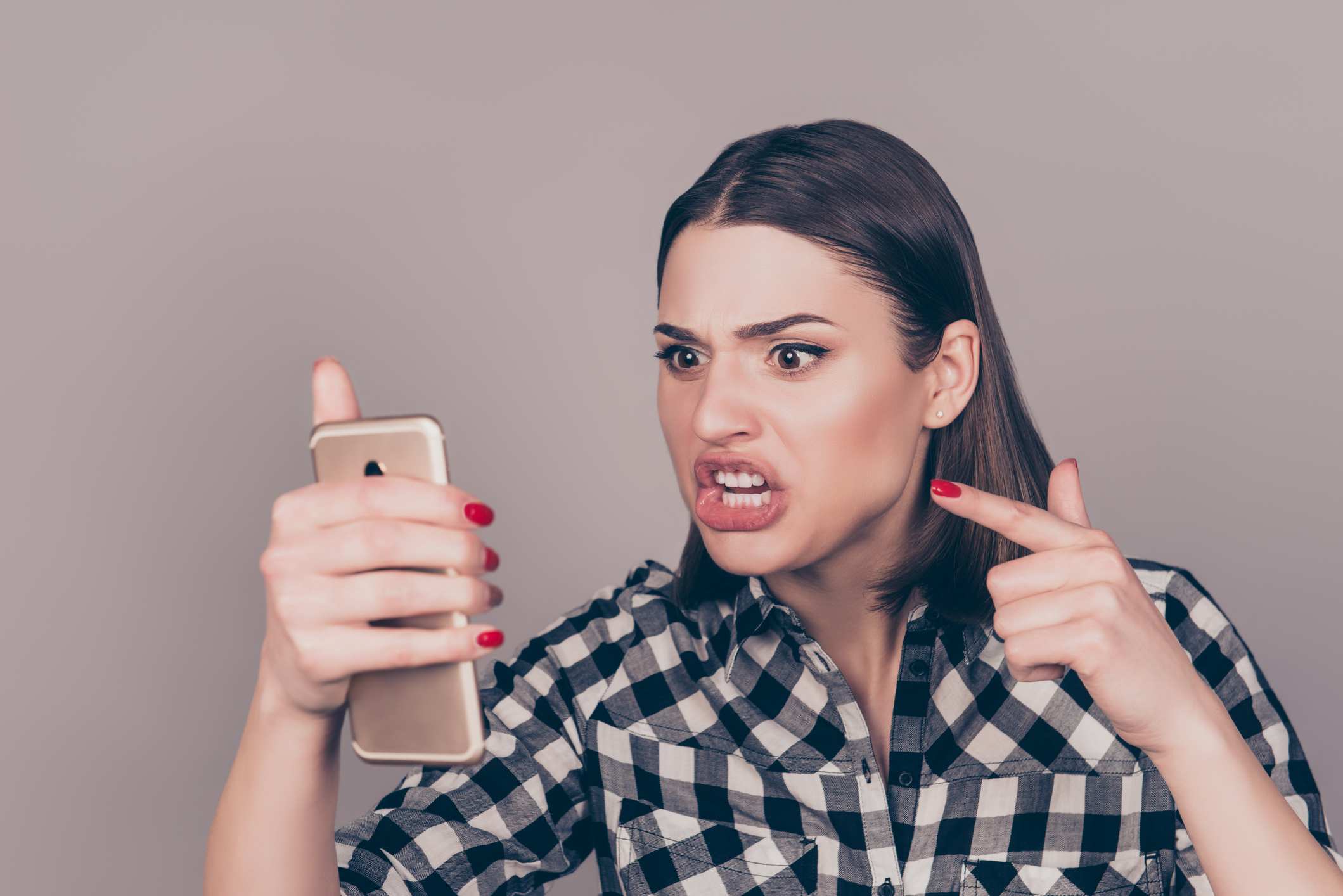 Young angry woman screaming at smartphone  while chatting with her boyfriend